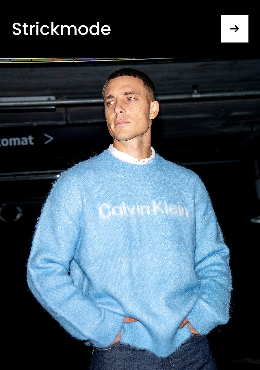 Ein lächelnder Mann in einem blauen Pullover und einer grauen Hose sitzt auf einem roten Teppich. Text: „Hose“.