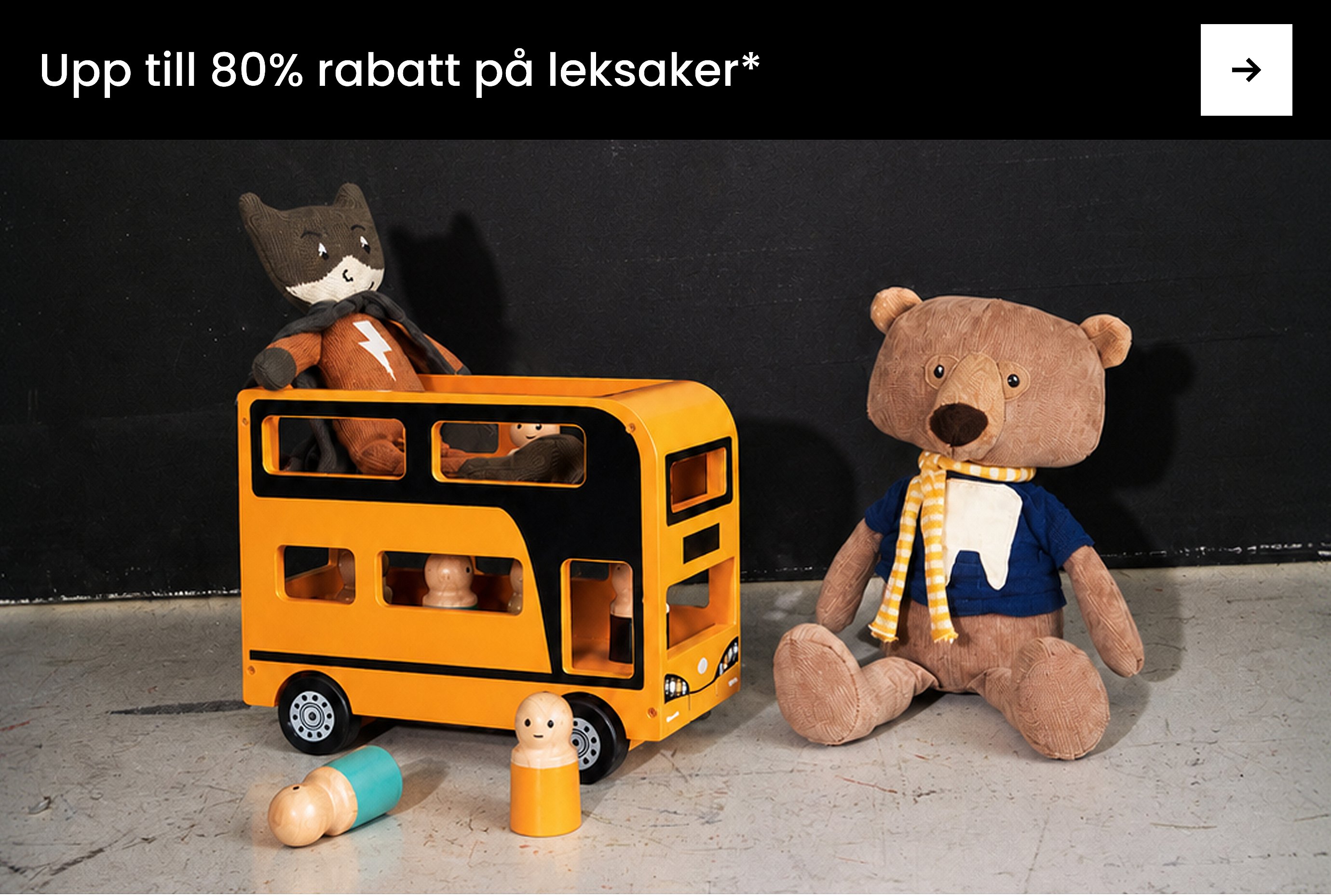 En leende pojke i vit skjorta och gröna byxor, framför en svart och grå vägg. Text: Basplagg från 60 kr, ENKEL STUDIO.