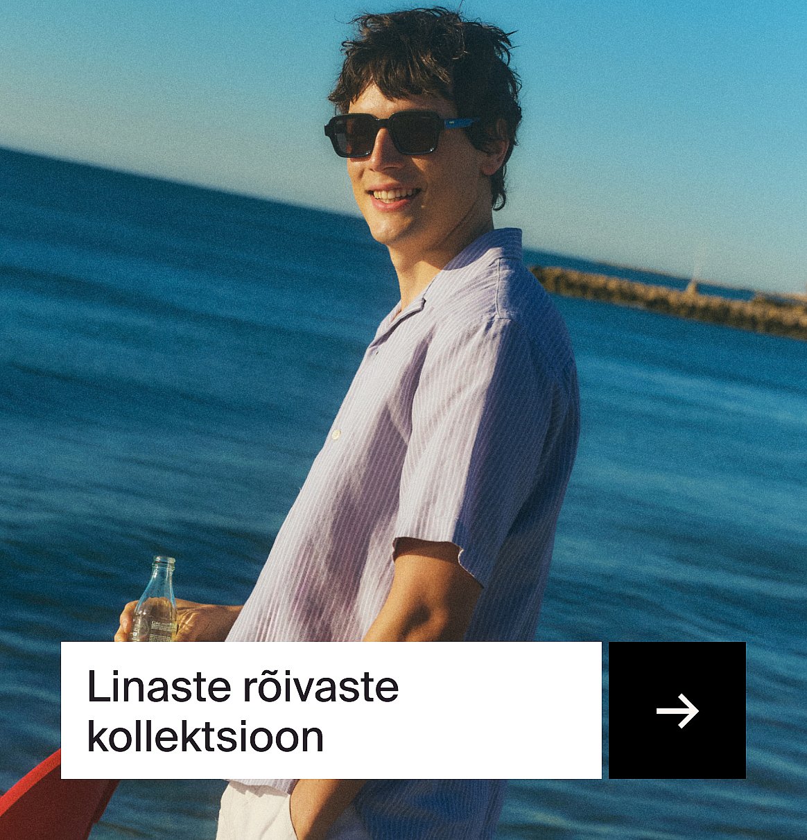 Naeratav mees lillas triibulises linases särgis ja päikeseprillidega mere ääres, pudel käes.
Tekst: Linane kollektsioon.