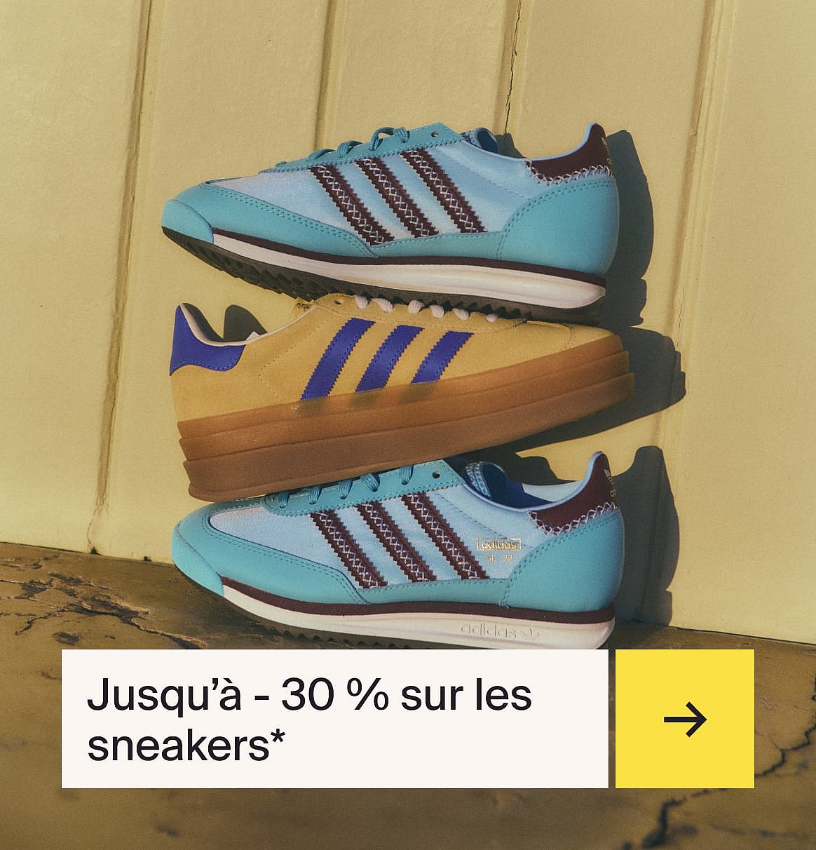 Three stacked sneakers against a yellow wall. Two blue with dark stripes, one tan with blue stripes. Text: "Jusqu'à - 30 %