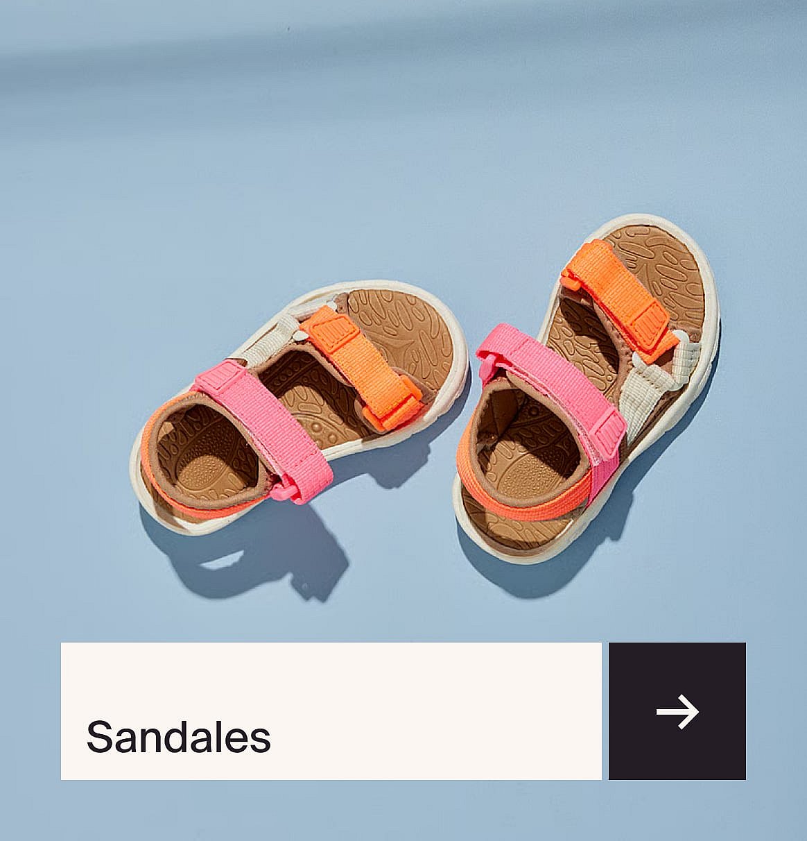 Pair of colorful sandals with pink and orange straps, white soles, and brown footbeds on a light blue surface.