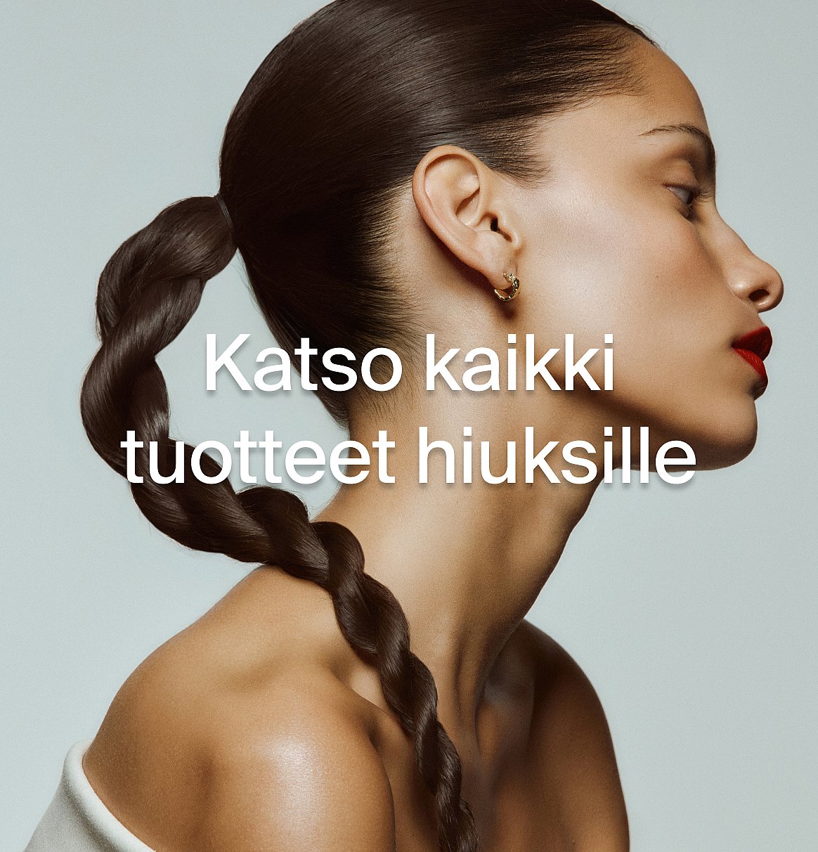 Naisen profiili, tumma letitetty poninhäntä, punaiset huulet, kultainen korvakoru. Tekstin päällekkäisyys: "Katso kaikki hiustuotteet."