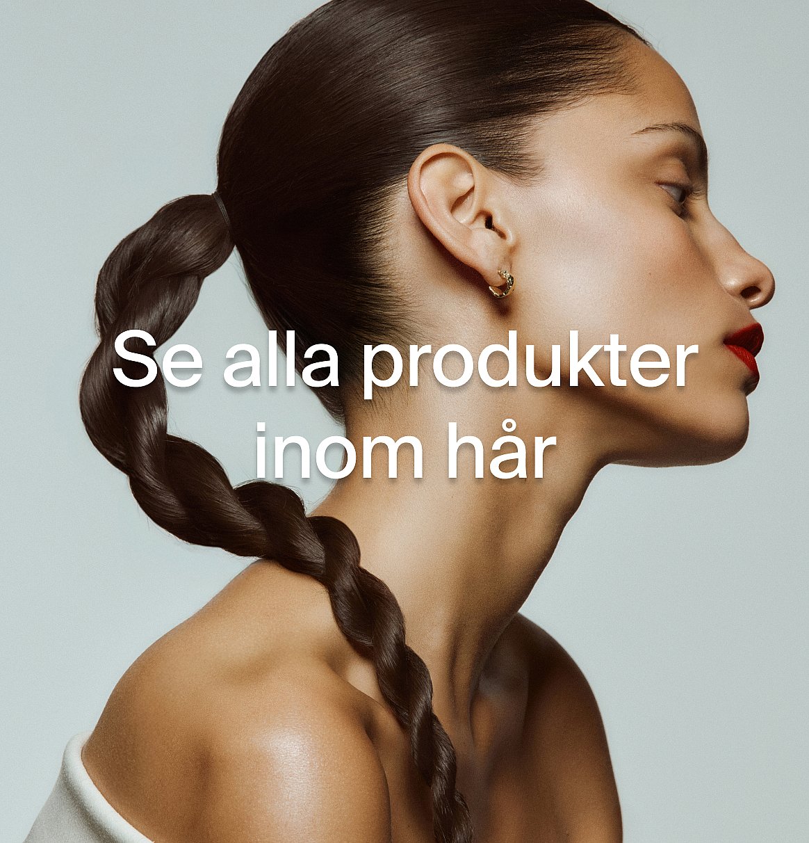 Kvinnoprofil, mörk flätad hästsvans, röda läppar, guldörhänge. Textöverlagring: "Se alla produkter inom hår."