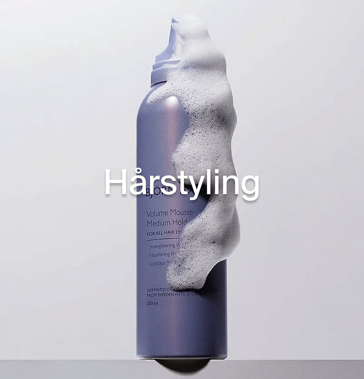 Lila hårmousseflaska med vitt skum som väller ut, på en ljus bakgrund. Med texten "Hårstyling".