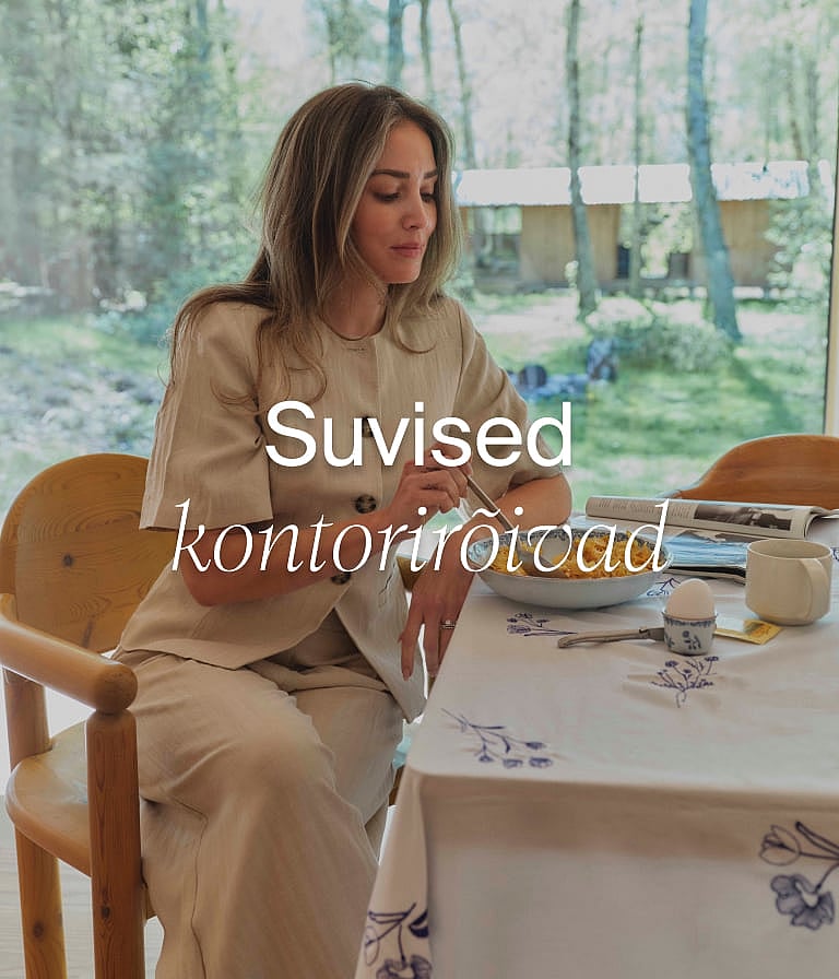 Naine heledas linases rõivastuses söömas einet mustrilise laudlinaga laua taga, akna ääres, mille taga on puud. Tekst: "Suvekontor"