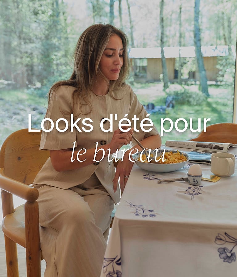 Femme en tenue de lin légère, prenant un repas à une table recouverte d'une nappe à motifs, près d'une fenêtre avec des arbres.
Bureau d'été