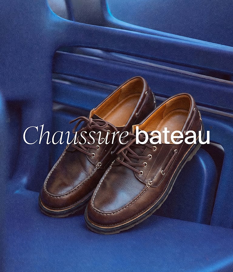 Une paire de chaussures bateau en cuir marron repose sur une surface bleue. En surimpression, un texte blanc affiche "Chaussures bateau".