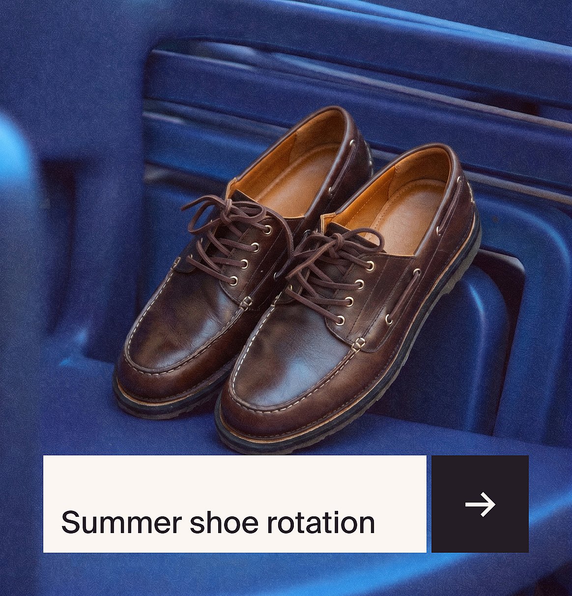 Een paar bruine leren mocassin-stijl veterschoenen met witte stiksels, op een blauw geribbeld oppervlak.