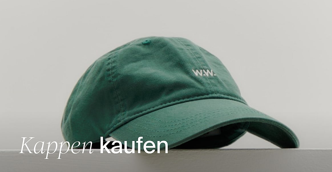 Grüeni Cap mit wiissem 'W.W.' Logo, uf ere Oberflächi vor hellem Hindergrund. Text: 'Chappe shoppe'