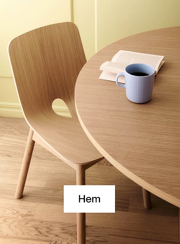 Ljus trästol och runt bord. Blå kaffemugg, öppen bok på bordet. Gul vägg, trägolv.