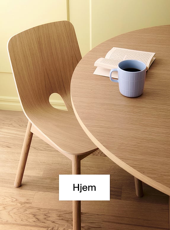 Lys trestol og rundt bord. Blå kaffekopp, åpen bok på bordet. Gul vegg, tregulv.