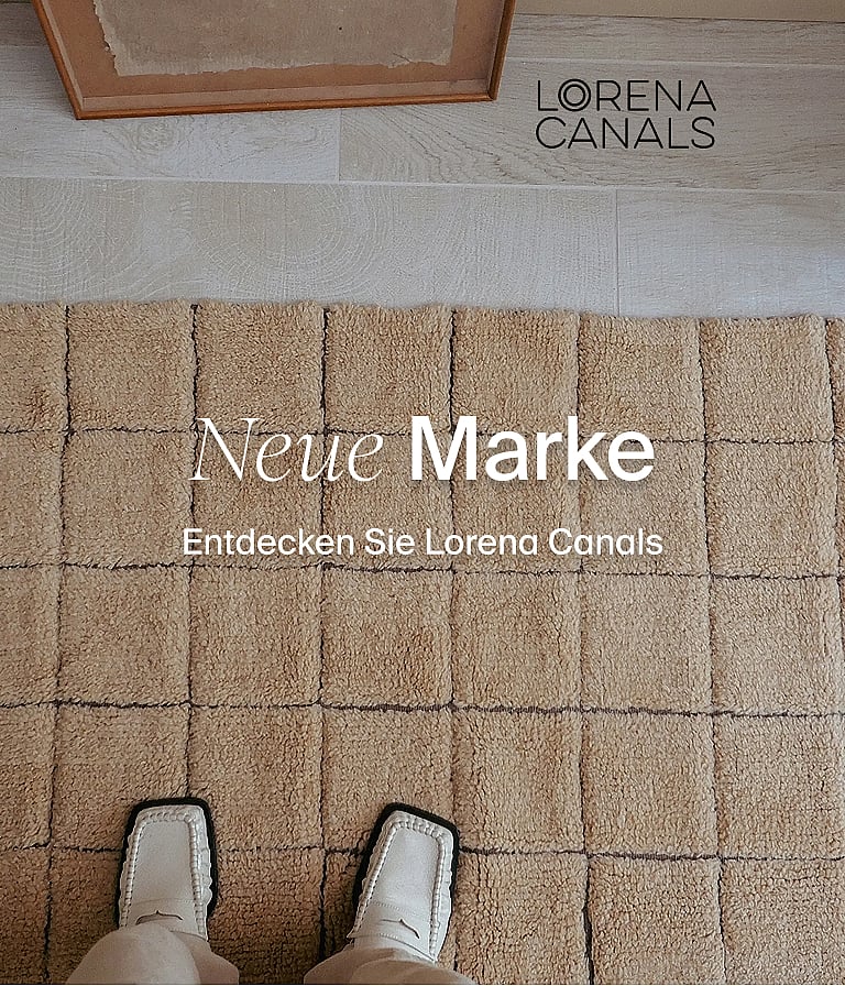 Füsse in weissen Schuhen auf einem beigen Teppich mit erhabener, quadratischer Struktur. Neue Marke. Entdecken Sie Lorena Canals.