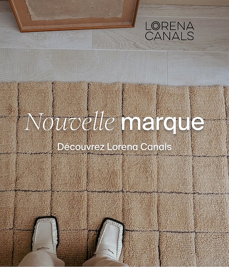 Pieds en chaussures blanches sur un tapis beige texturé avec des motifs carrés en relief. Nouvelle marque Découvrez Lorena Canals.