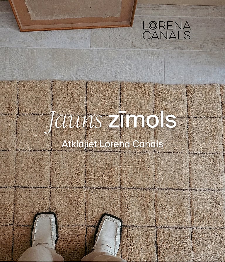 Pēdas baltos apavos uz teksturēta smilškrāsas paklāja ar paceltām kvadrātveida sekcijām. Jauns zīmols. Atklājiet Lorena Canals.