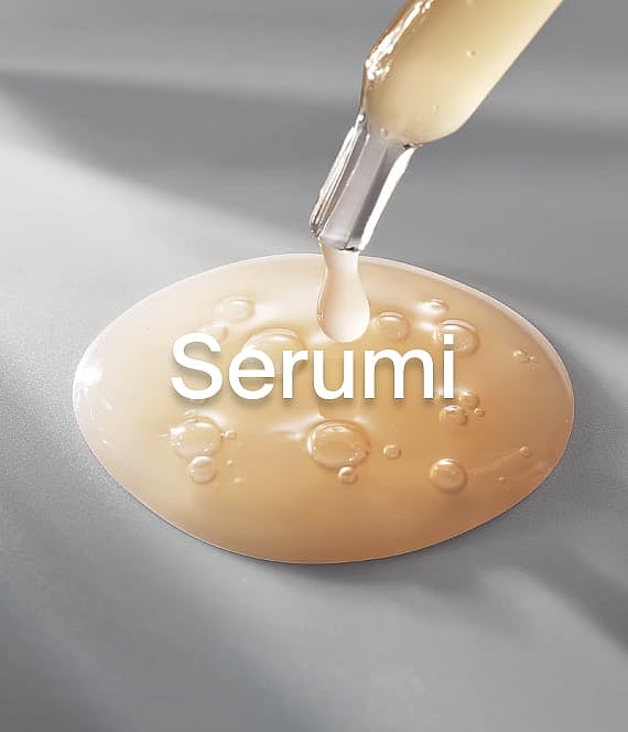 Pipete nomet zeltainu seruma pilienu uz ovālas seruma peļķes ar burbuļiem uz pelēkas virsmas.
Serums.