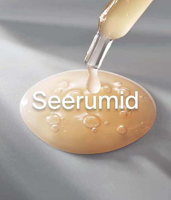Pipett tilgutab kuldse seerumitilga ovaalsele seerumiloigule mullidega hallil pinnal.
Seerum.