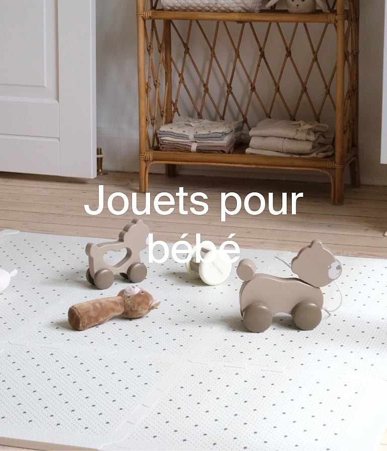 Wooden and plush baby toys on a dotted playmat. Rattan shelf in background. Text overlay: Jouets pour bébé.