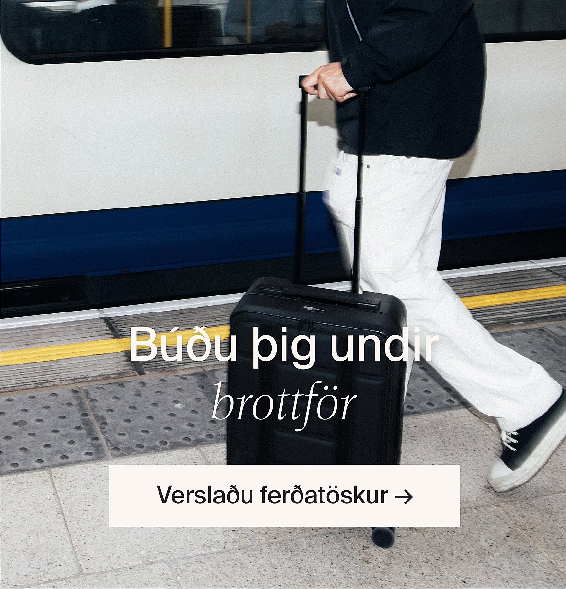 Manneskja í hvítum götóttum stuttermabol og bláum gallabuxum, með hendur í vösum, stendur við ljósan viðarvegg.
