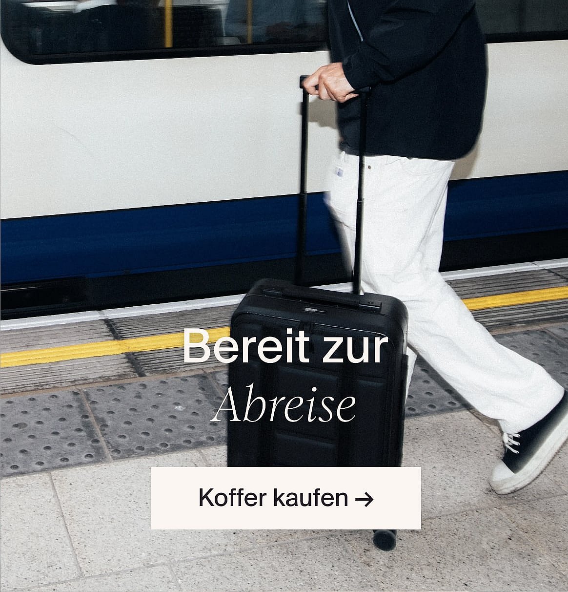 Modell in weisser Kurzarm-Bluse mit Lochstickerei und blauer Jeans, Hände in den Taschen, vor einer hellen Holzwand.