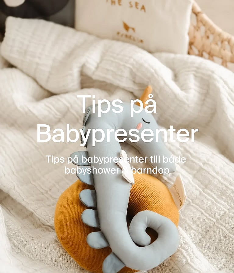 Light blue plush seahorse on a mustard yellow cushion, resting on a white textured blanket. Text: Tips på Babypresenter.
