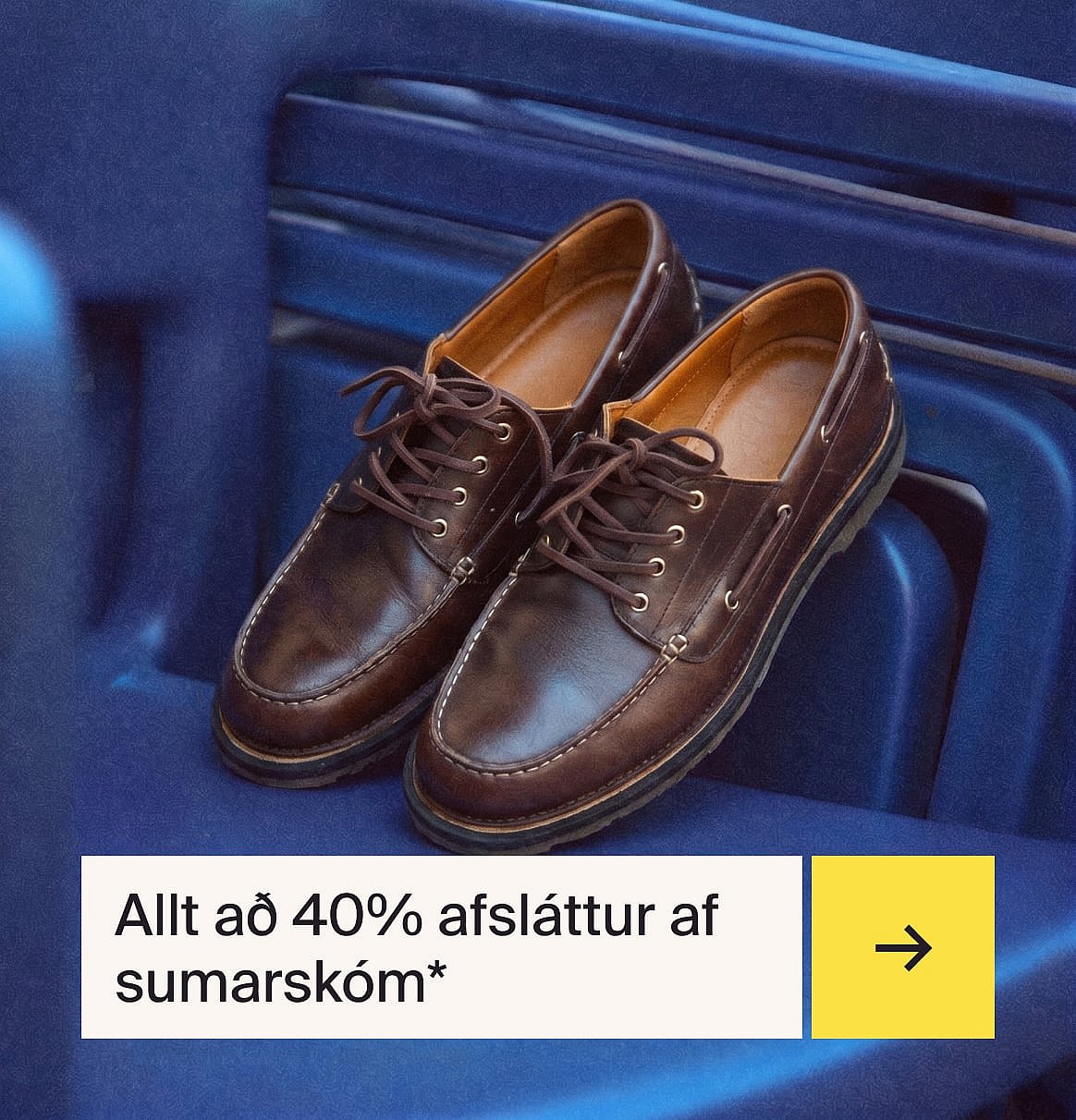 Par af brúnum reimaðum leðurskóm í mokkasínstíl með hvítum saumum, á bláu riffluðu yfirborði.