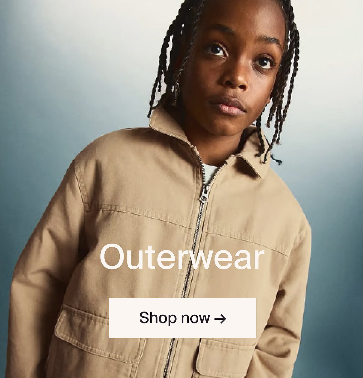 Child with braided hair in a tan jacket, looking up. Blue-grey background. Text: Outerwear, Shop now.
