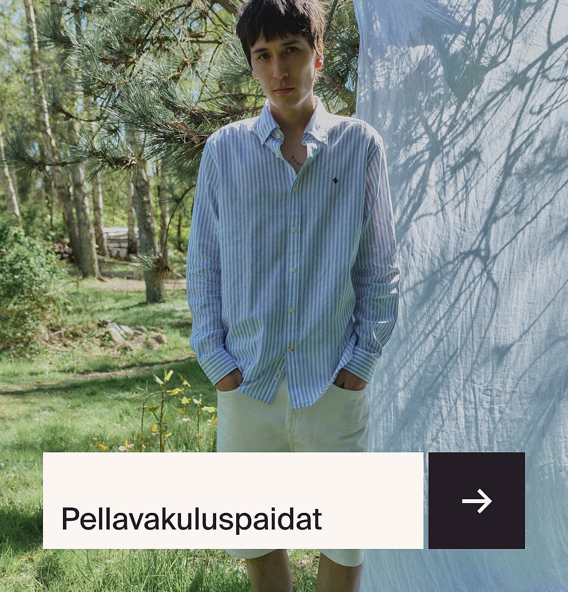 Mies vaaleansinisessä paidassa ja beigessä pellavapuvussa istuu ulkopöydän ääressä mansikkakakun kanssa puutarhassa.