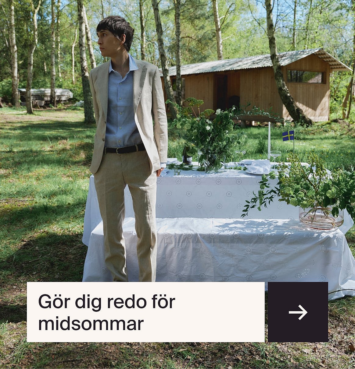 Man i ljusblå skjorta och beige linnekostym sitter vid ett utomhusbord med en jordgubbstårta i en trädgård.