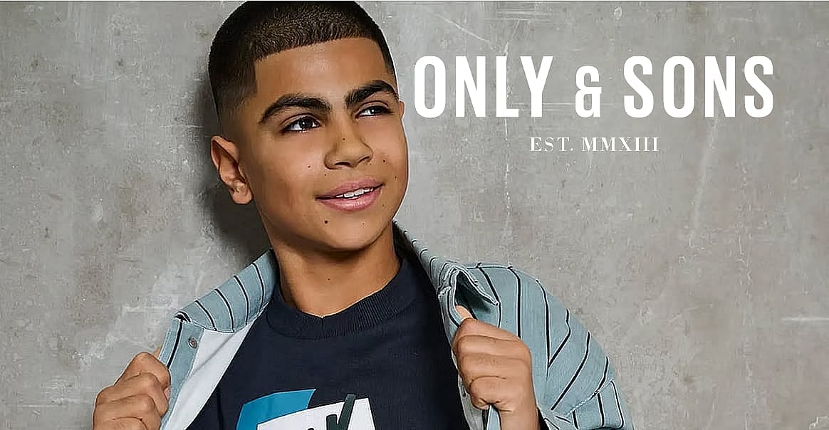 Smiling boy in striped shirt, looking up, against a concrete wall. ONLY & SONS EST. MMXIII branding.
