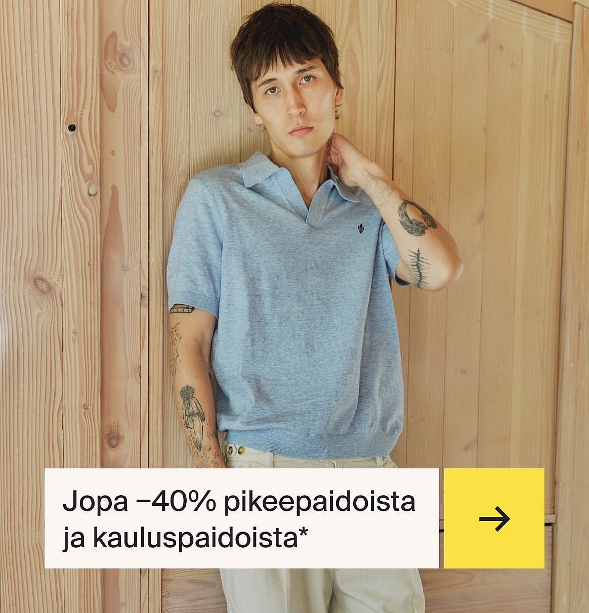 Mies vaaleansinisessä paidassa ja beigessä pellavapuvussa istuu ulkopöydän ääressä mansikkakakun kanssa puutarhassa.