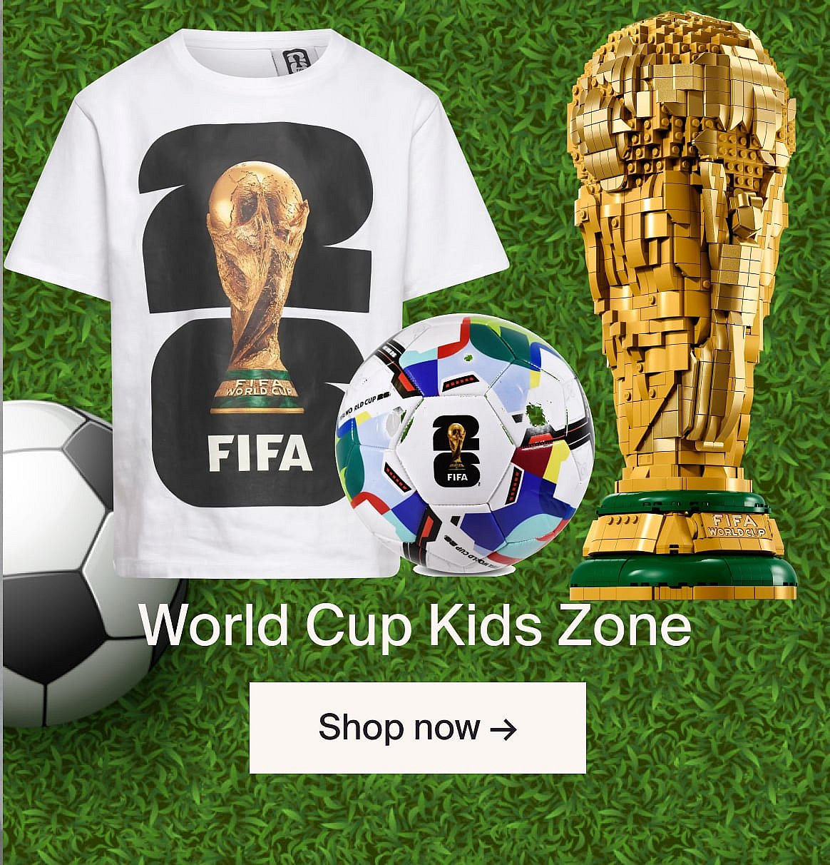 FIFA World Cup merchandise on grass: white t-shirt with trophy, colorful soccer ball, large golden LEGO trophy.