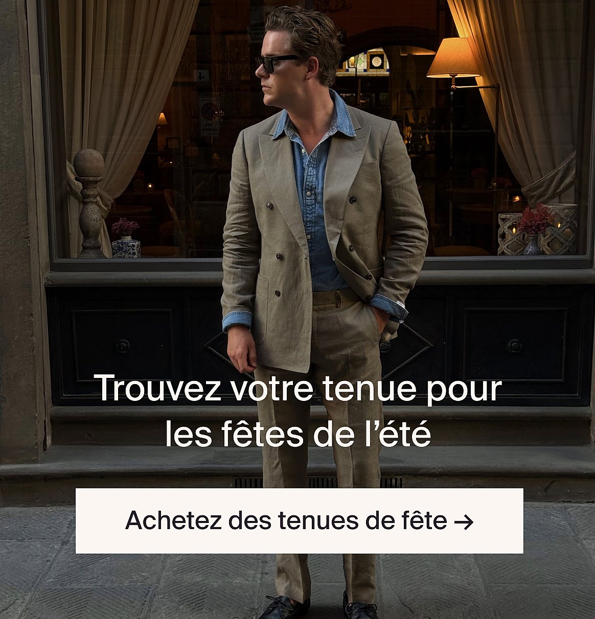 Personne en chemise blanche à manches courtes en broderie anglaise et jean bleu, les mains dans les poches, debout contre un mur en bois clair.