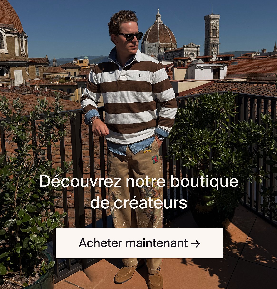 Homme en costume beige clair et chemise bleue en extérieur, près d'une table avec de la verdure, dans une clairière en forêt.