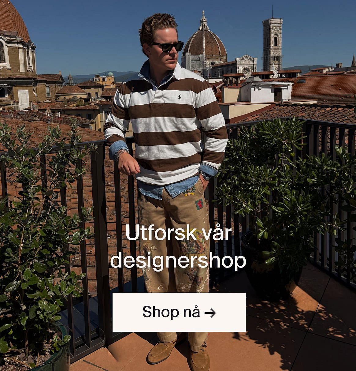 Mann i en lys beige dress og blå skjorte utendørs, ved et bord med grønne planter, på en skogslysning.