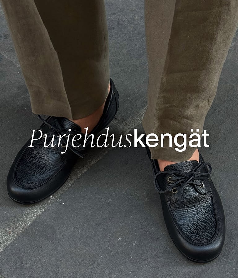Henkilö ruskeissa shortseissa, valkoisessa paidassa ja sinisessä takissa pitää punavartisia kasveja ulkona puuseinän vieressä.