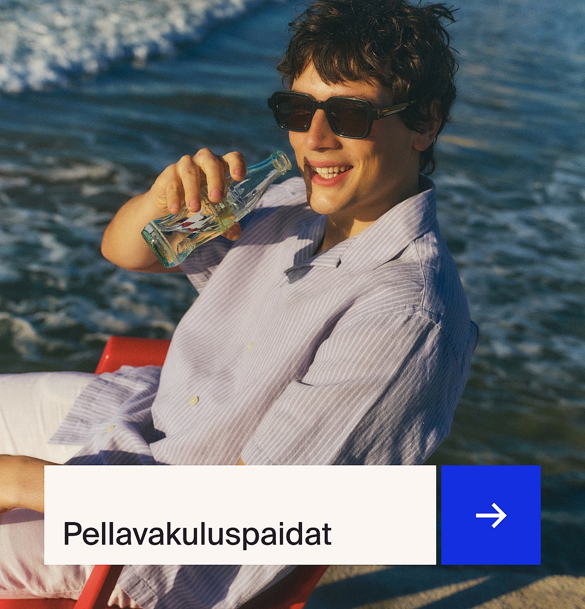 Mies vaaleansinisessä paidassa ja beigessä pellavapuvussa istuu ulkopöydän ääressä mansikkakakun kanssa puutarhassa.