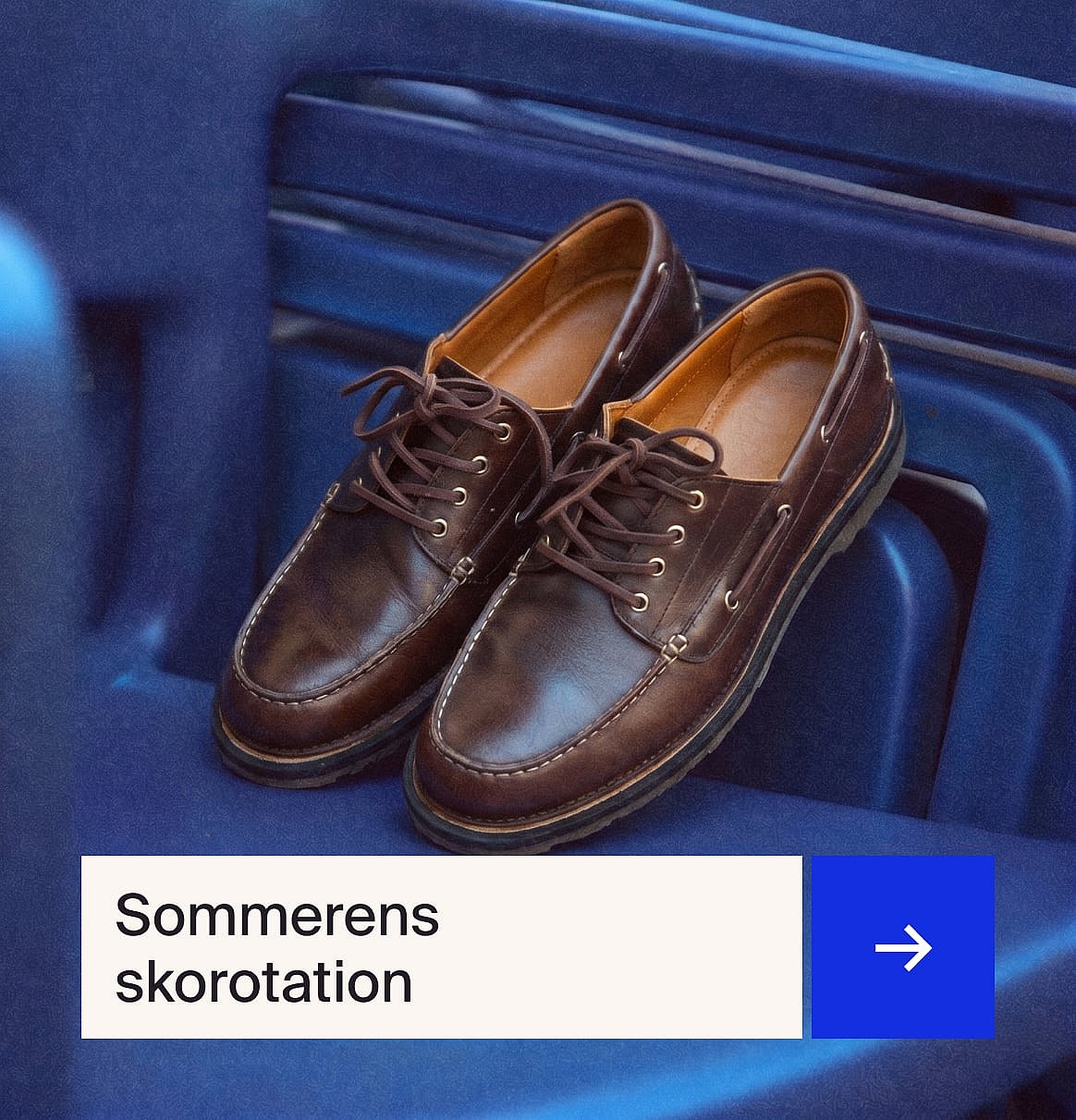 Et par brune snøresko i læder i mokkasin-stil med hvide syninger, der hviler på en blå ribbet overflade.
