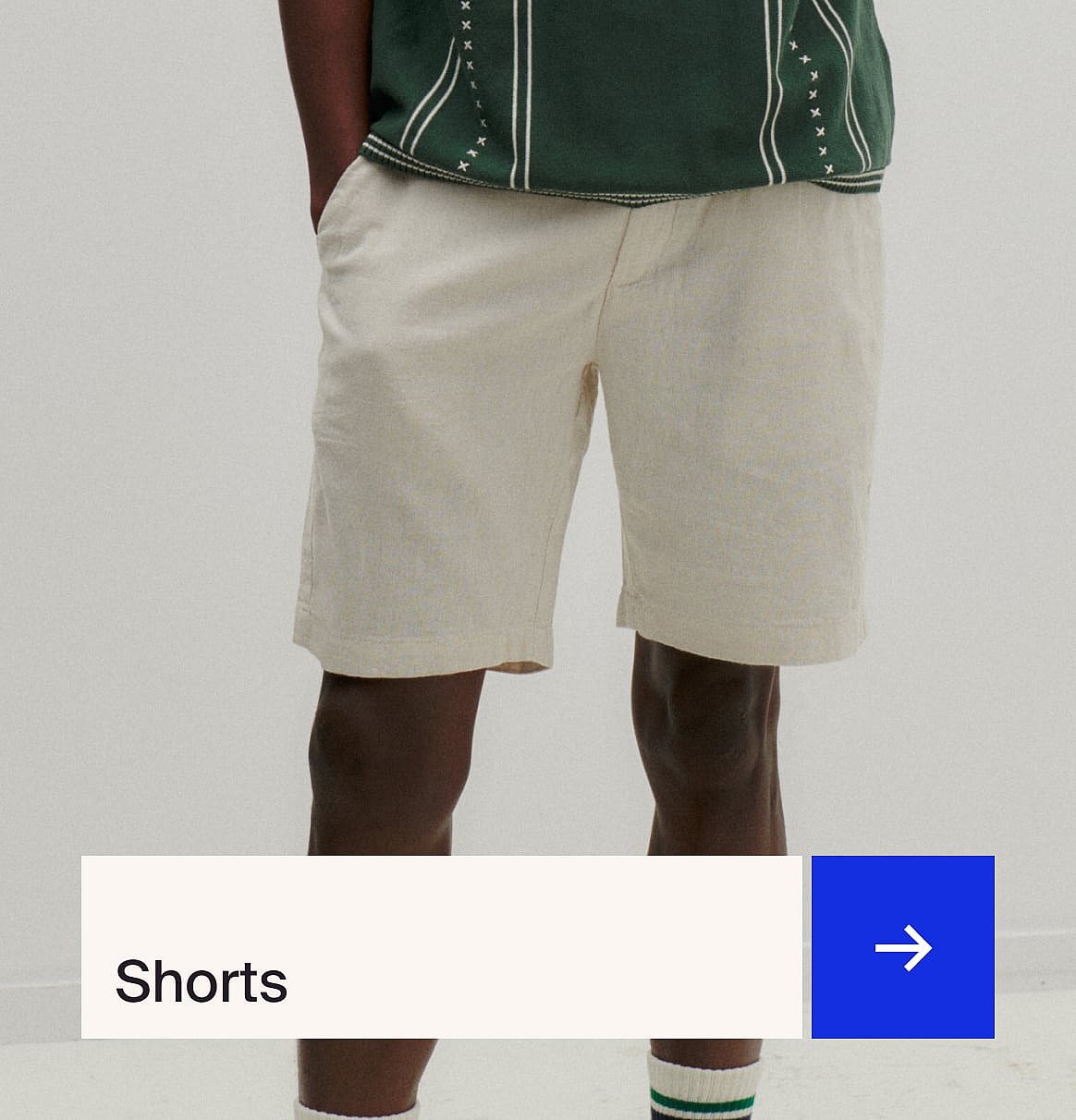 Mand i stribet skjorte, kasket og sort slingbag, set bagfra, mod røde og hvide vægge. Teksten "Festival-looks".