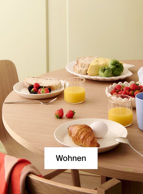 Heller Holzstuhl und runder Tisch. Blauer Kaffeebecher, offenes Buch auf dem Tisch. Gelbe Wand, Holzboden.