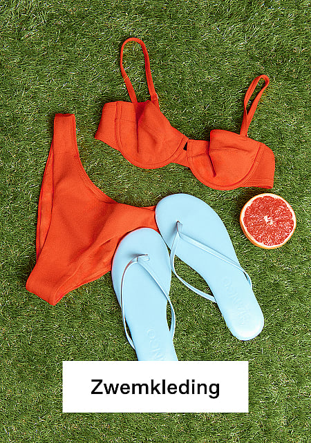 Een oranje bikini, lichtblauwe teenslippers en een halve grapefruit, neergelegd op groen gras.