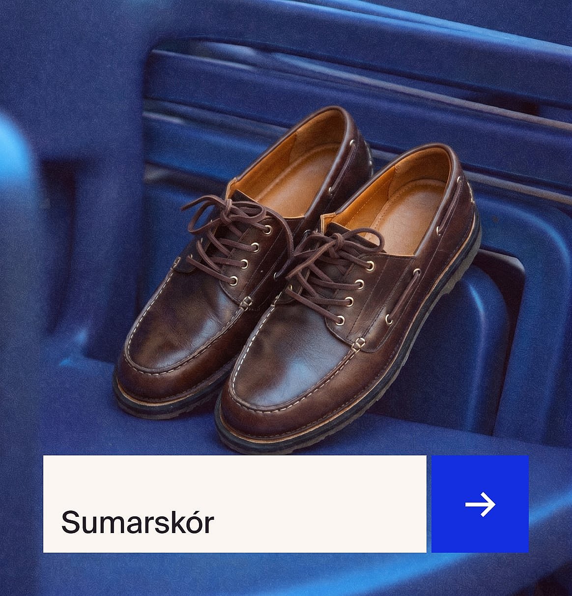 Par af brúnum reimaðum leðurskóm í mokkasínstíl með hvítum saumum, á bláu riffluðu yfirborði.