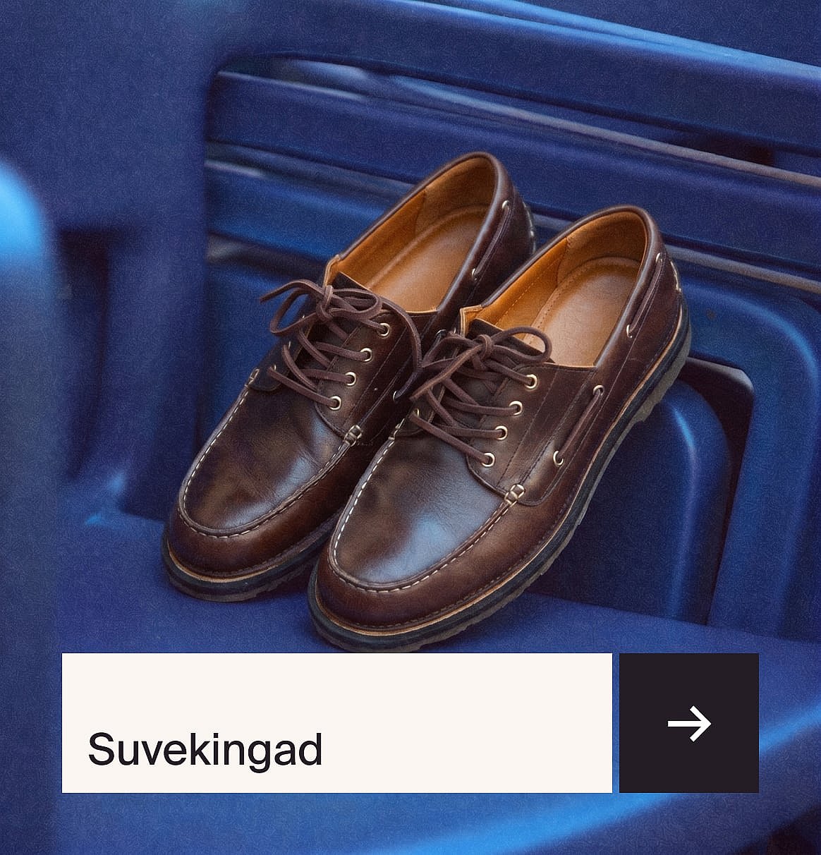 Pruunid paeltega nahast mokassiin-stiilis kingad valgete õmblustega, puhkamas sinisel soonilisel pinnal.