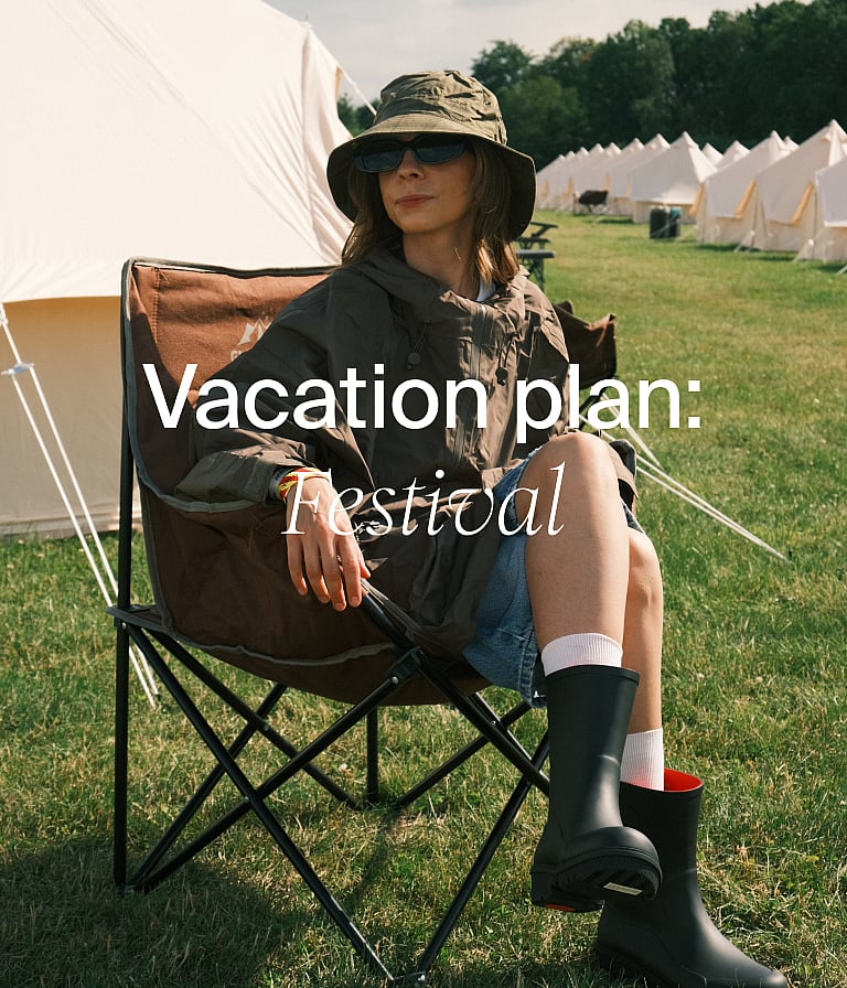 Smiling woman in a cream cable-knit cardigan with green trim, in a forest with a cabin. "Summer knitwear" text.