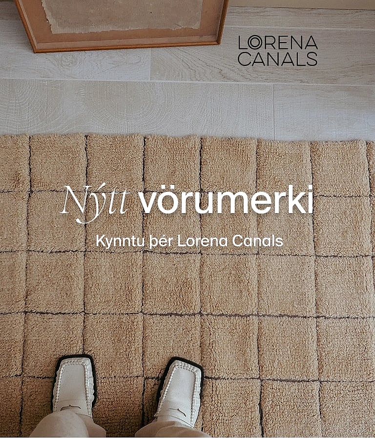 Fætur í hvítum skóm á áferðarmikilli ljósbrúnni mottu með upphækkuðum ferköntuðum köflum. Nýtt vörumerki. Uppgötvaðu Lorena Canals.