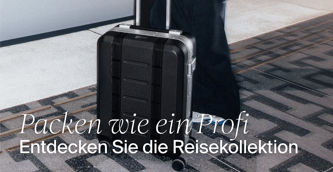 Türkis gestreifte Badeshorts hängen an einer Wäscheleine, mit einem sonnigen Strand und dem Meer im Hintergrund. Text: Badeshorts shoppen.
