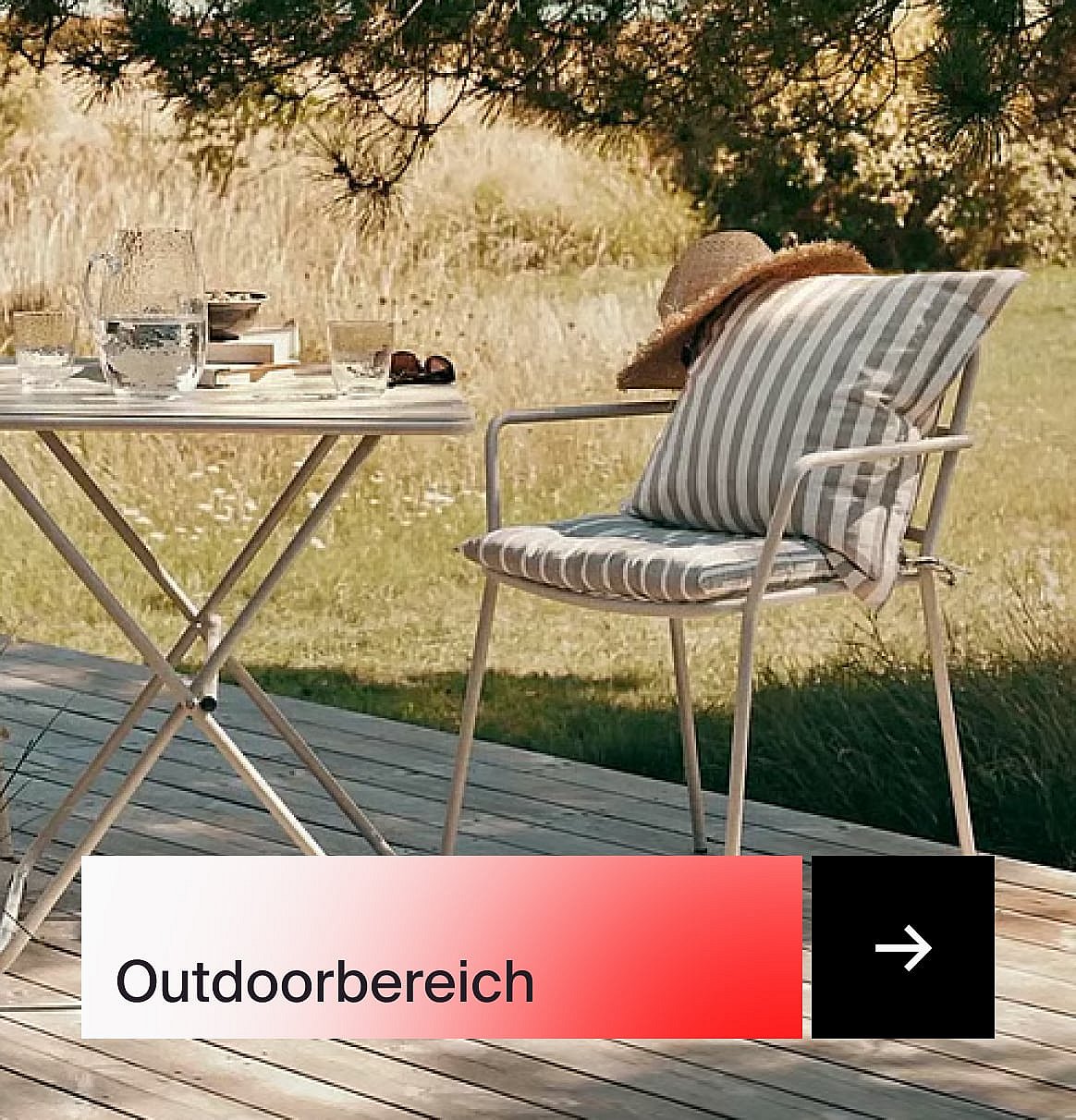 Ein Gartenstuhl mit gestreiften Kissen und einem Strohhut, neben einem Tisch mit Getränken auf einer Holzterrasse.
