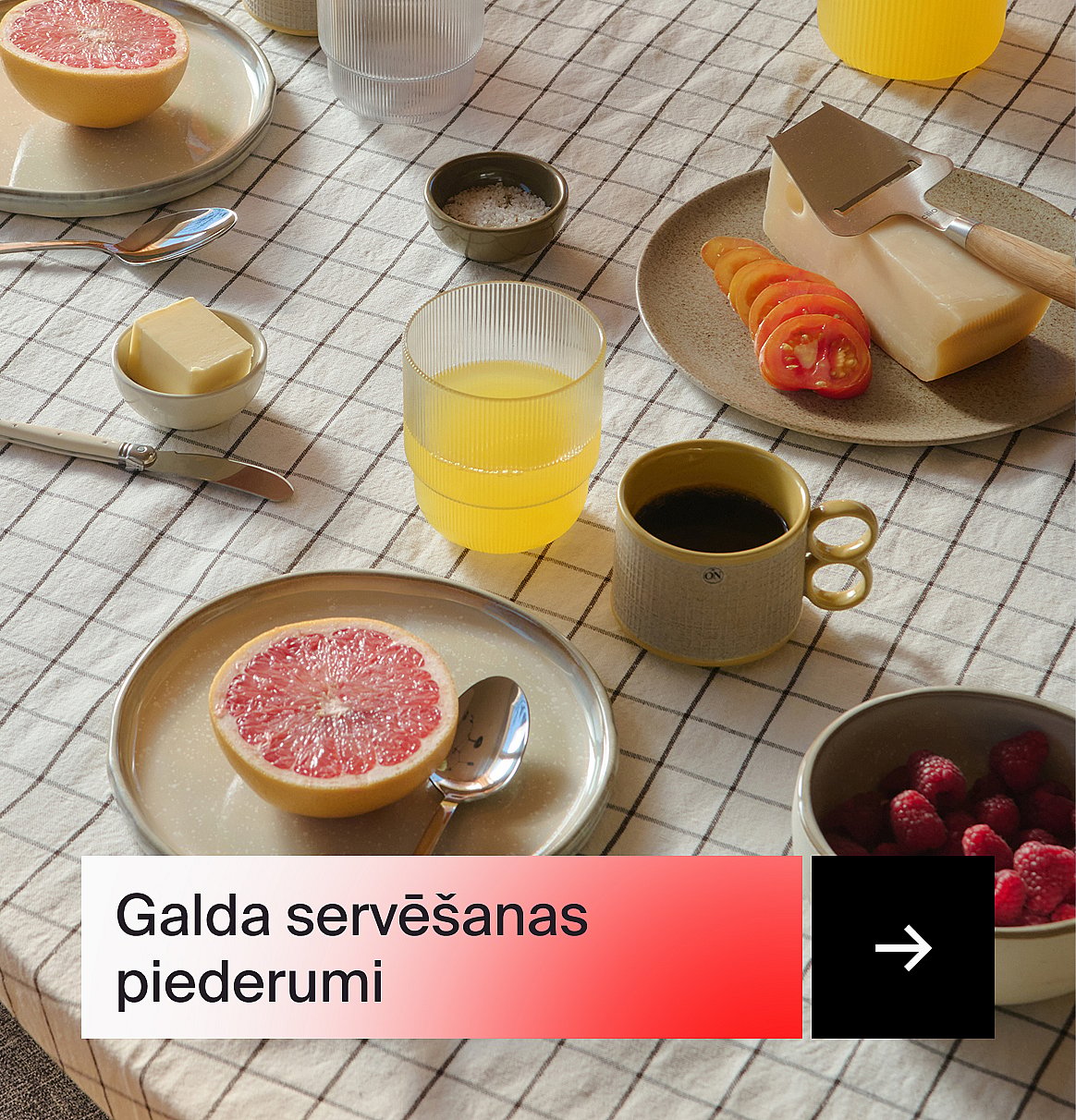 Brokastu galds ar greipfrūtiem, sulu, kafiju, sieru, tomātiem, sviestu un avenēm uz rūtainas galdautas.