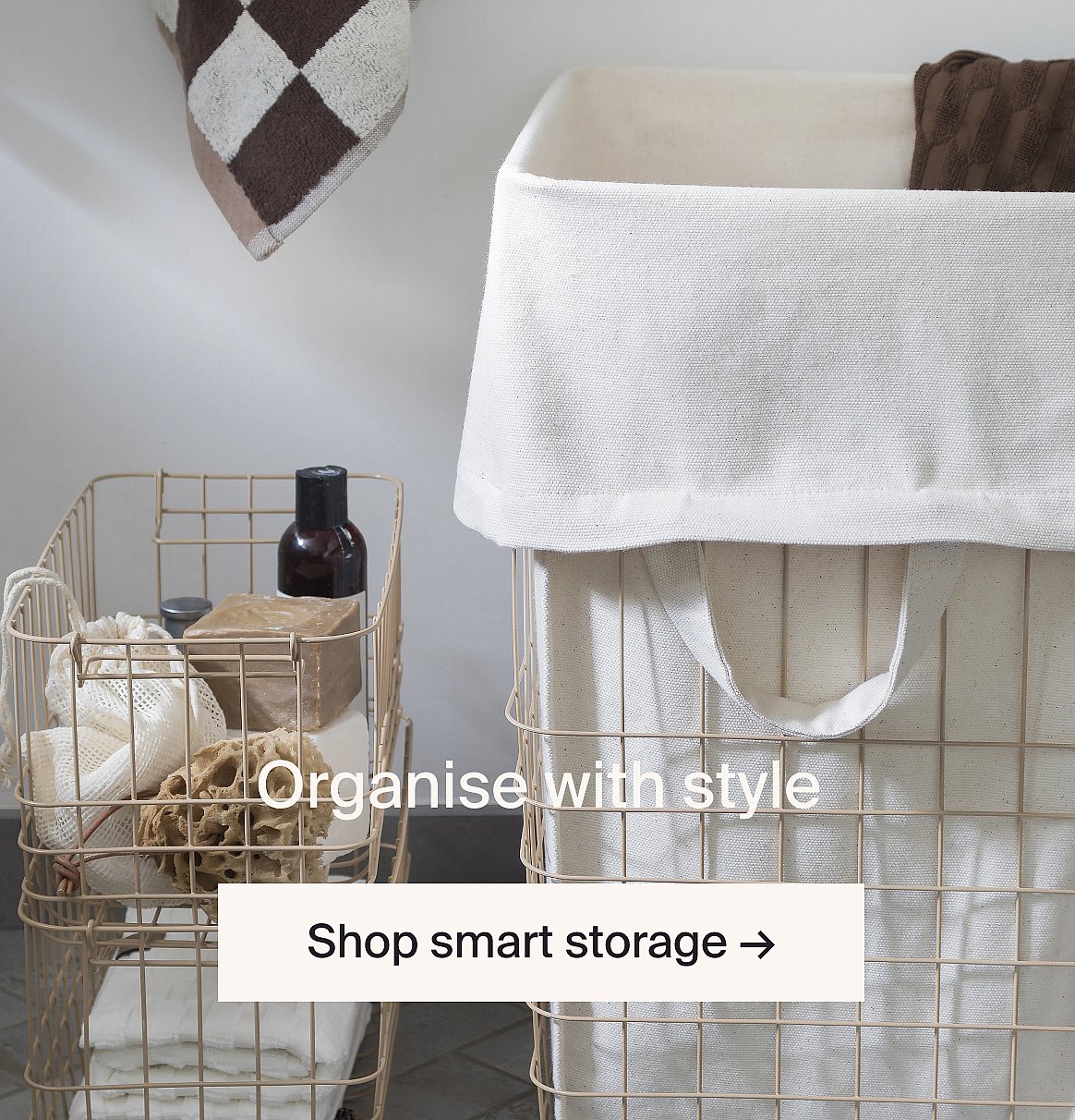 Two beige wire storage baskets with white fabric liners. One holds bath items, the other is a laundry hamper.