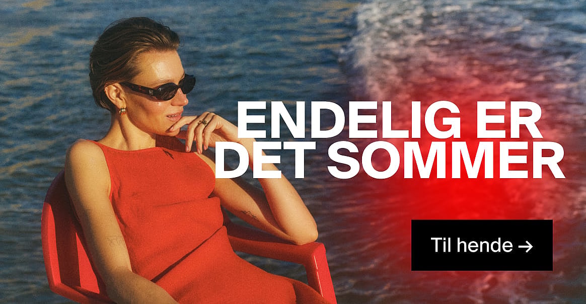 Kvinde i rød kjole og solbriller, med hånden mod hagen, ved det blå vand. Teksten »SUMMER IS HERE« og »For hende →«.
