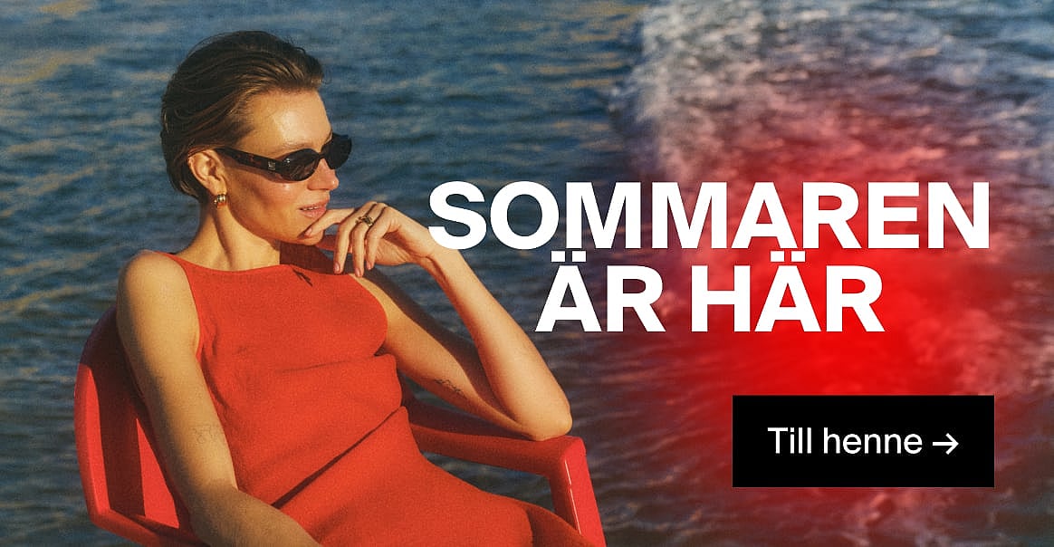 En kvinna i röd klänning och solglasögon, med handen mot hakan, vid blått vatten. Texten ”Sommaren är här” och ”Till henne →”.